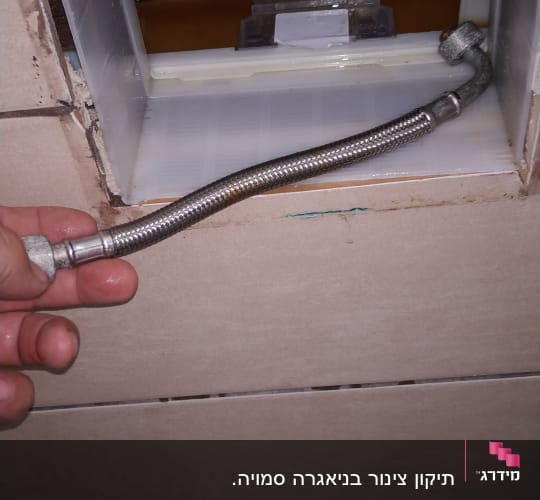 יד מחזיקה צינור גמיש ליד קיר פתוח